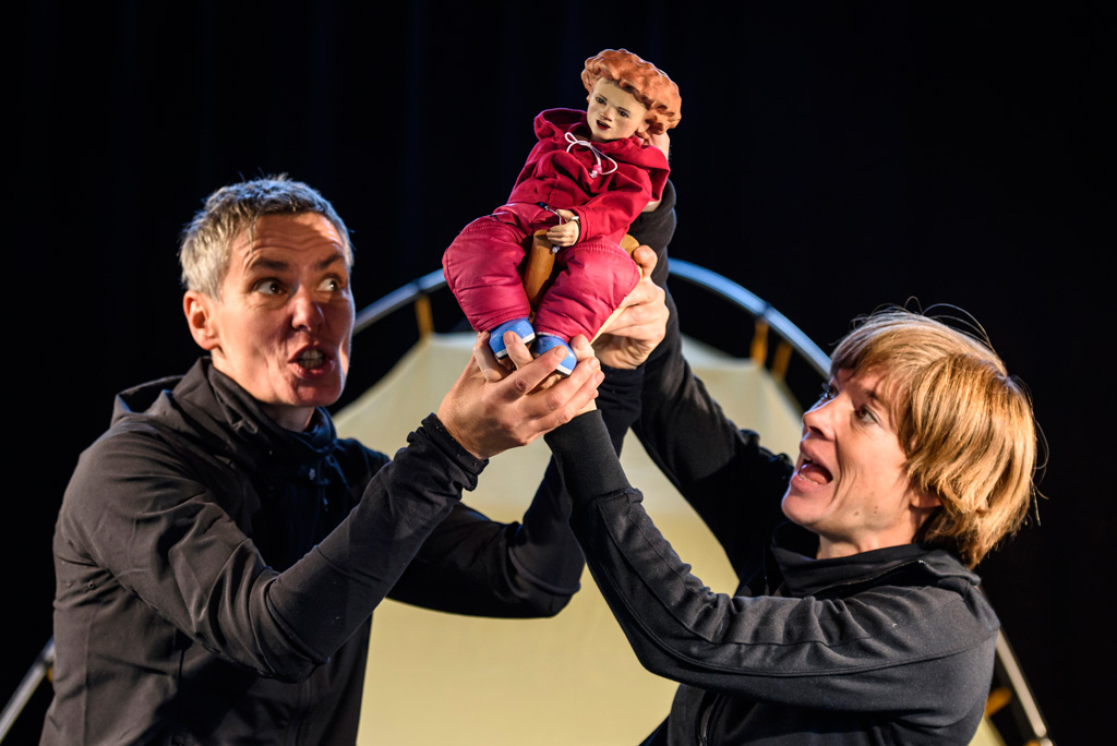 Zwei Schauspieler, Mann und Frau spielen mit einer Puppe im Figurentheater.